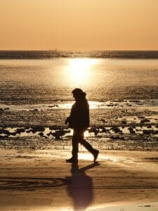 a person walking on the beach at sunset