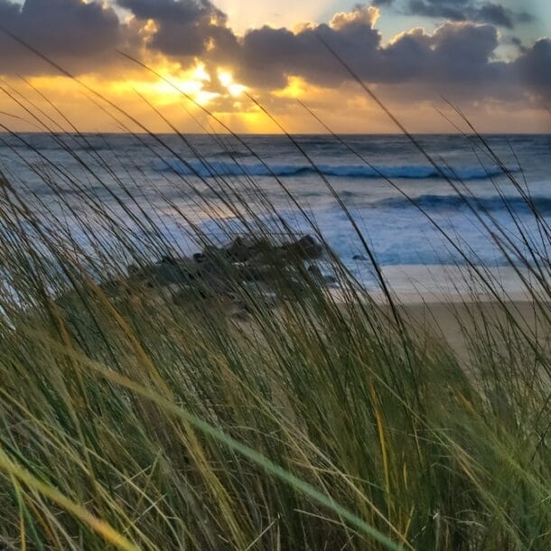 the sun is setting over the ocean and the beach