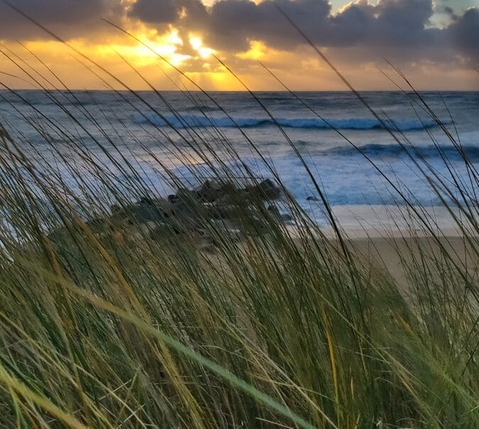 the sun is setting over the ocean and the beach